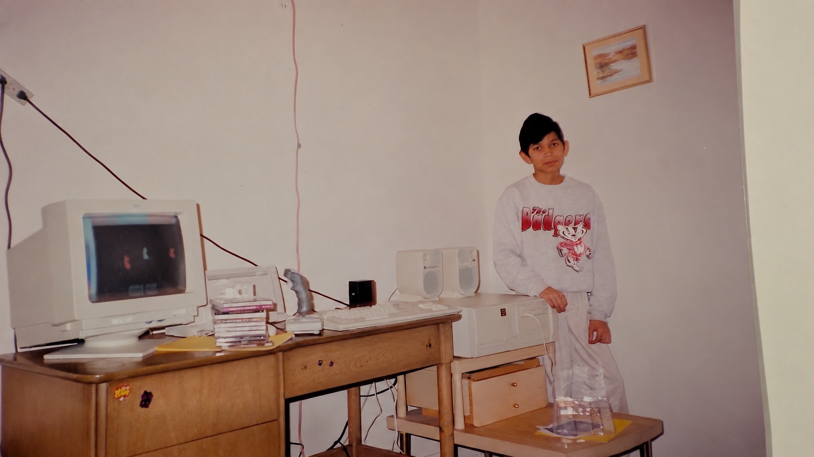 Tarique as a child standing beside a desktop computer with a CRT monitor.