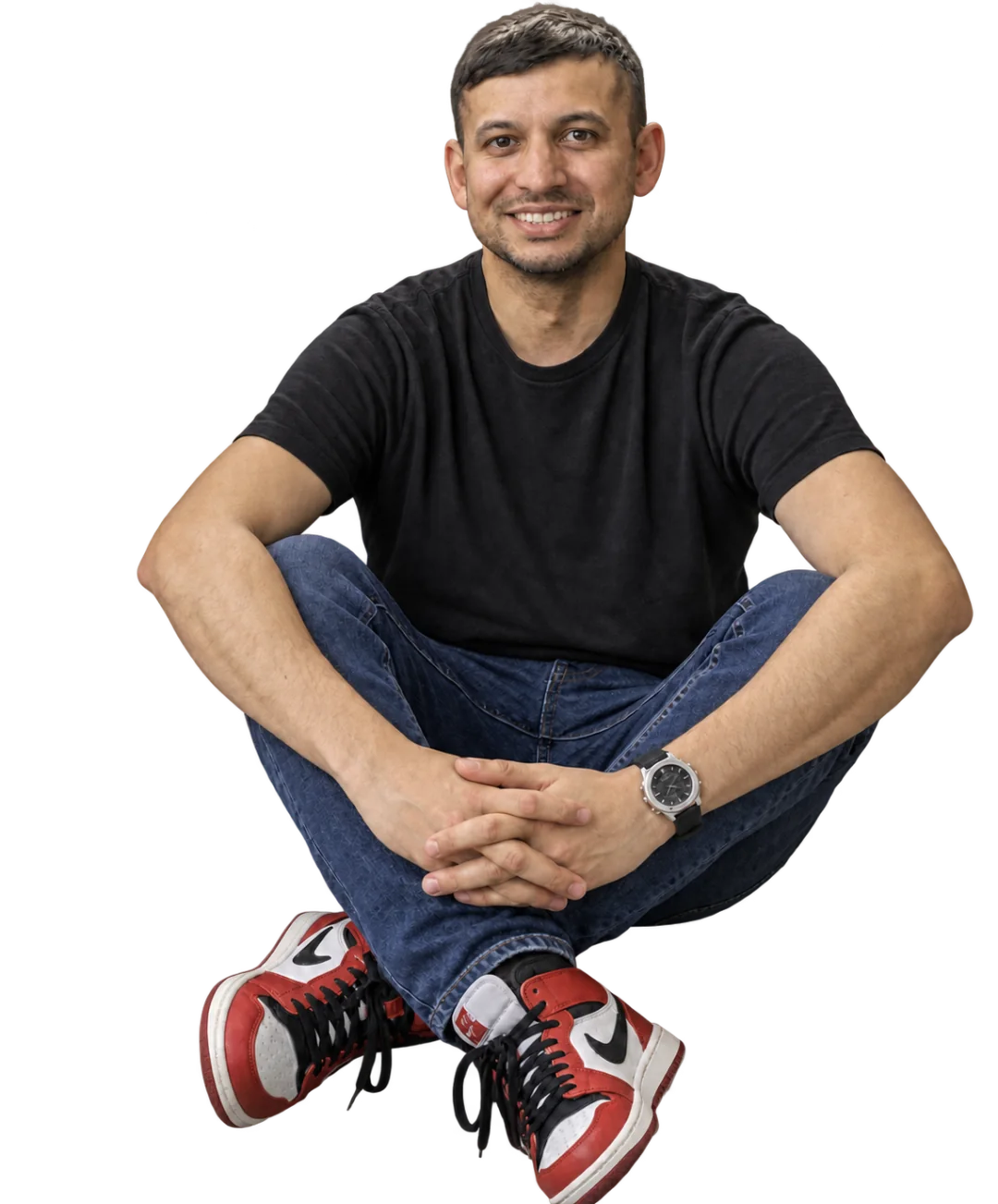 Tarique seated casually, wearing a black shirt, jeans and red trainers.